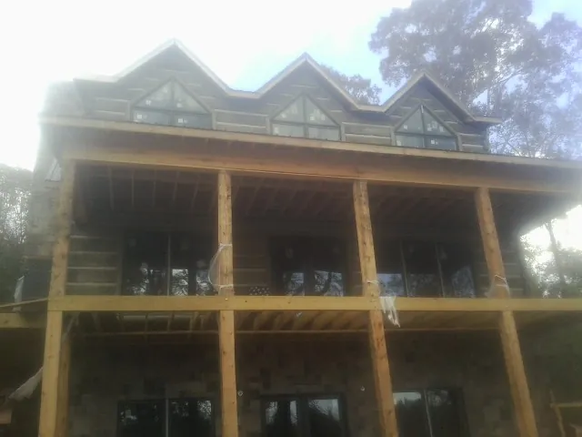 Dormers and porch framing on a large log home under construction — Roof Coating work by our crew in Stryker