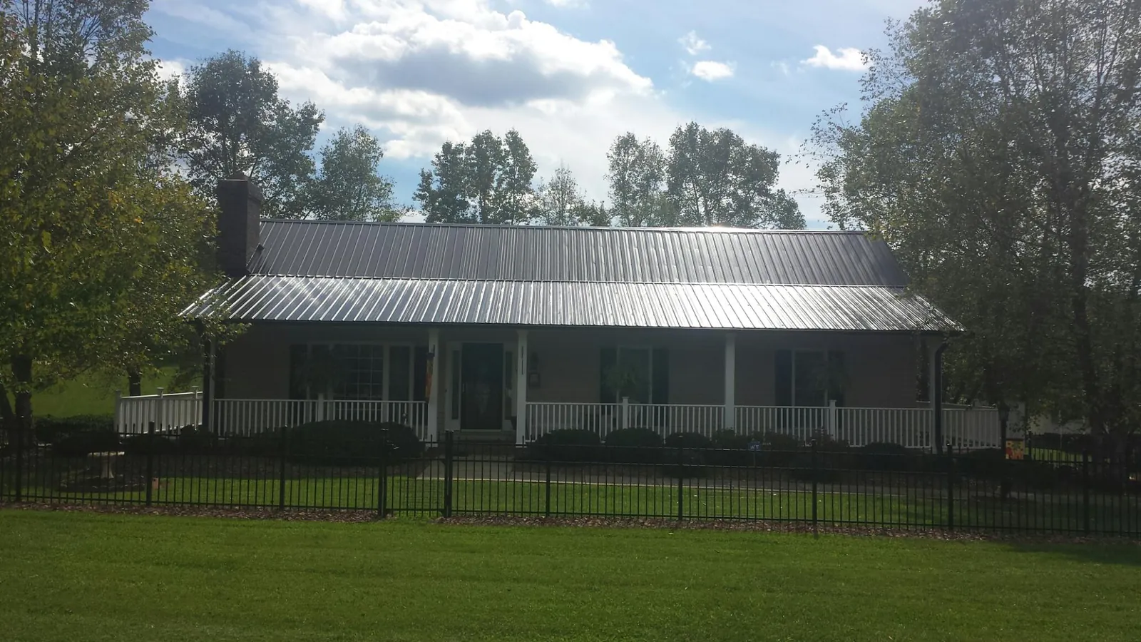Gray metal roof on a brick ranch with a full width front porch — Gutter Guard Installation work by our crew in Stryker