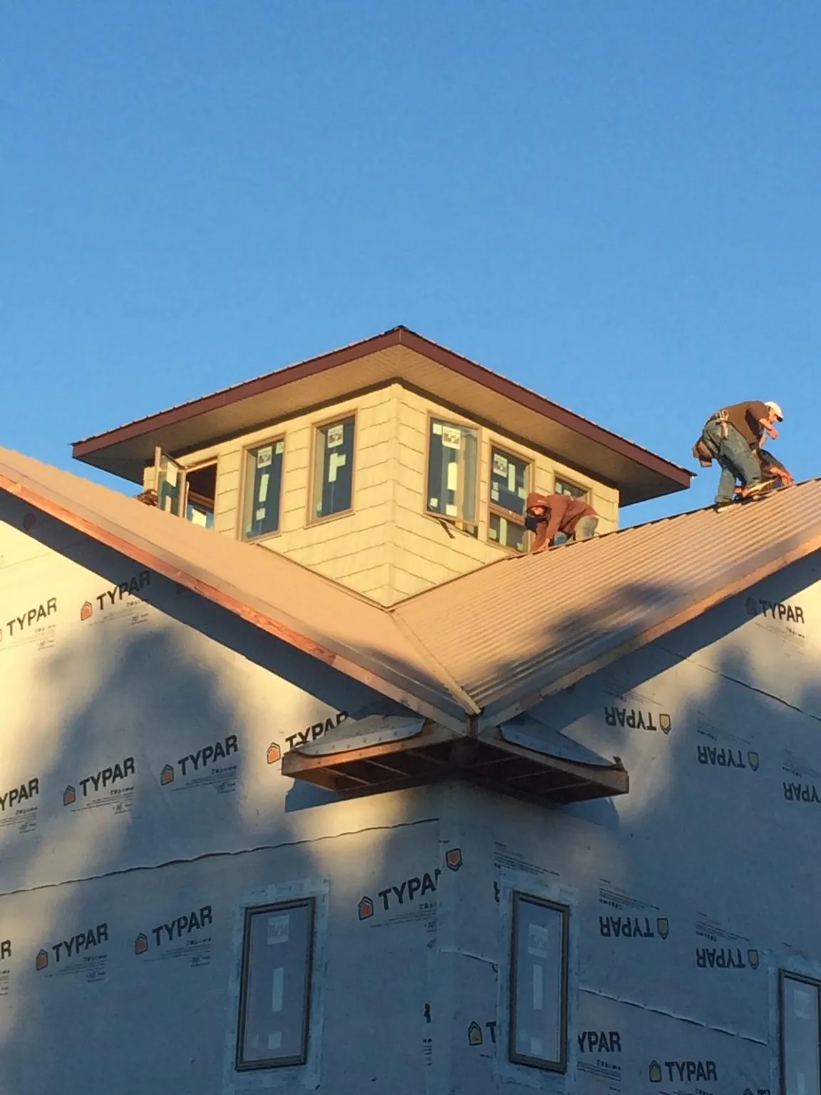 Roofers working around a rooftop cupola on a new metal roof at sunset — Roof Waterproofing in Stryker by Roofing Brothers